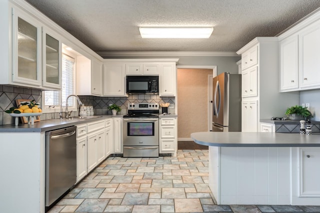 kitchen with appliances with stainless steel finishes, white cabinetry, sink, backsplash, and crown molding