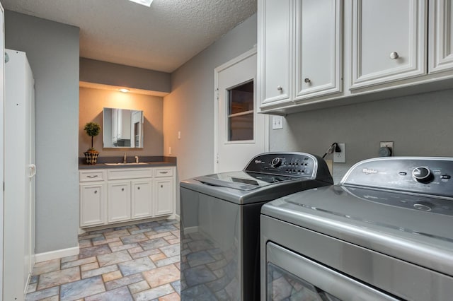 laundry room featuring cabinets, separate washer and dryer, sink, and a textured ceiling