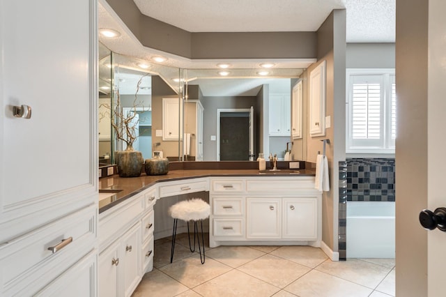 bathroom featuring vanity, a textured ceiling, tile patterned floors, and a bathtub