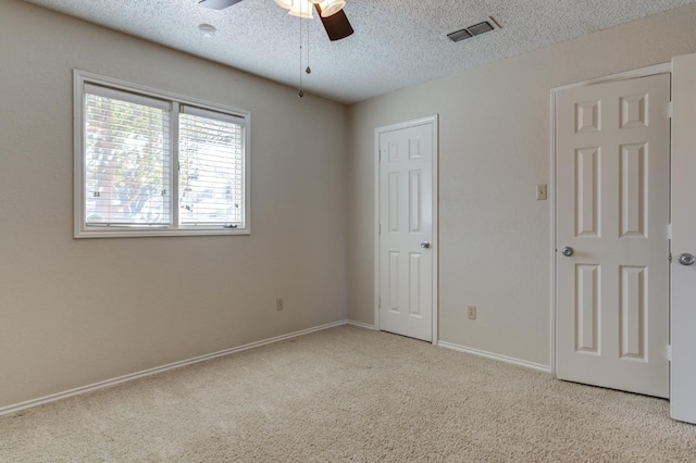 carpeted spare room with ceiling fan and a textured ceiling