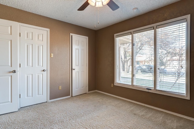 unfurnished bedroom with ceiling fan, light carpet, and a textured ceiling