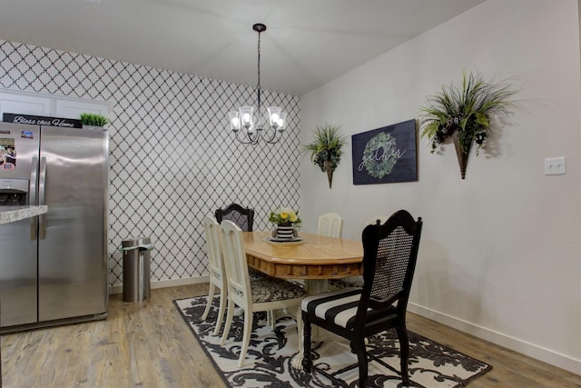 dining area featuring light wood-style floors, a notable chandelier, baseboards, and wallpapered walls