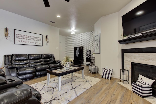 living room with visible vents, a high end fireplace, ceiling fan, wood finished floors, and baseboards