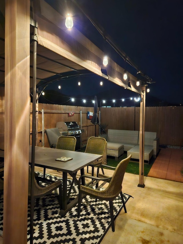 patio at night with outdoor lounge area, outdoor dining area, area for grilling, and fence