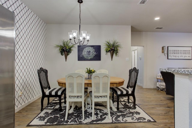 dining space with a chandelier, visible vents, and wood finished floors