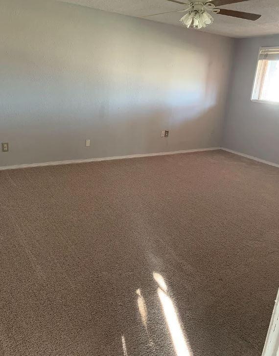 carpeted spare room with a textured ceiling and ceiling fan