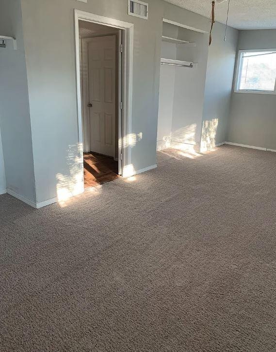 unfurnished bedroom with a closet, a textured ceiling, and dark colored carpet