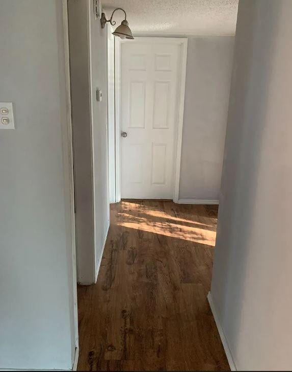 corridor with dark hardwood / wood-style flooring and a textured ceiling