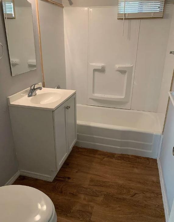 full bathroom with vanity, hardwood / wood-style floors,  shower combination, and toilet