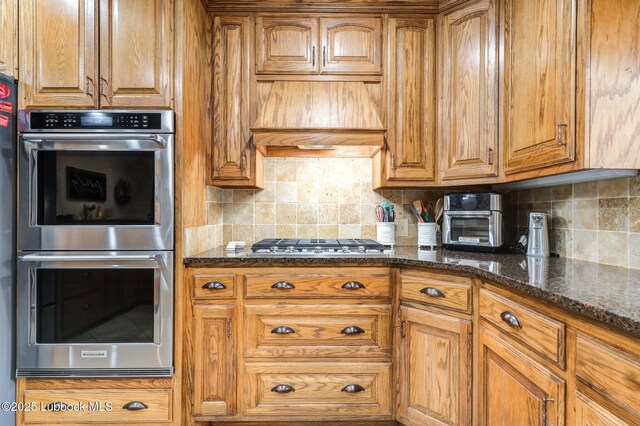 4510 21st St, Lubbock, TX 79407 - kitchen with appliances with stainless steel finishes, tasteful backsplash, custom exhaust hood, and brown cabinetry