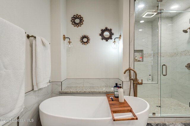 4510 21st St, Lubbock, TX 79407 - full bath featuring a marble finish shower, tile walls, a freestanding tub, and wainscoting