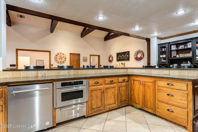 4510 21st St, Lubbock, TX 79407 - kitchen featuring appliances with stainless steel finishes, a warming drawer, a textured ceiling, brown cabinets, and light tile patterned floors