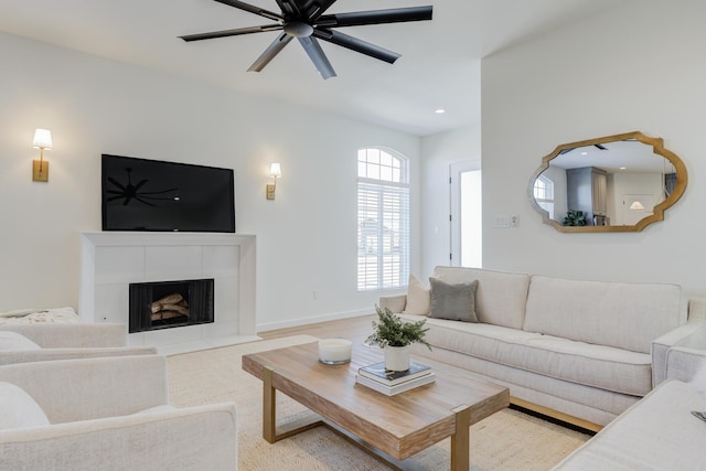 living room featuring a tile fireplace and ceiling fan