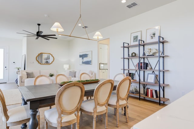 dining space with ceiling fan and light hardwood / wood-style flooring