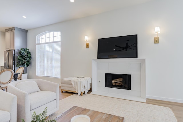 living room featuring a tile fireplace and light hardwood / wood-style flooring