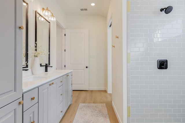 bathroom with vanity, wood-type flooring, and a tile shower