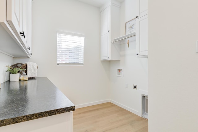 laundry area featuring electric dryer hookup, washer hookup, light hardwood / wood-style flooring, and cabinets