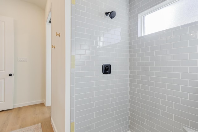 bathroom featuring wood-type flooring and tiled shower