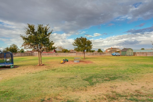 view of yard featuring a trampoline and a storage unit