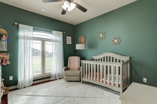 bedroom featuring a nursery area and ceiling fan