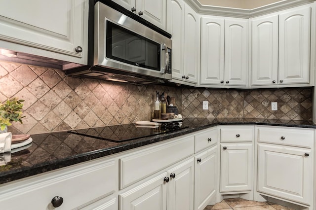 kitchen featuring white cabinets, black electric cooktop, and decorative backsplash