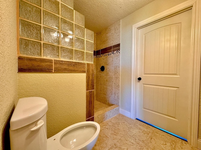 bathroom featuring toilet, a textured ceiling, and a tile shower