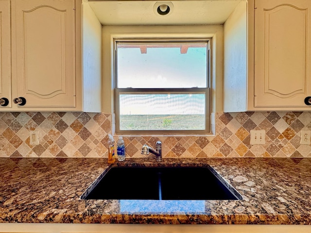 kitchen featuring white cabinetry, sink, dark stone countertops, and decorative backsplash