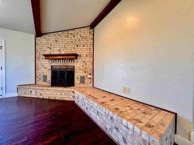 unfurnished living room with a brick fireplace, hardwood / wood-style floors, and vaulted ceiling with beams