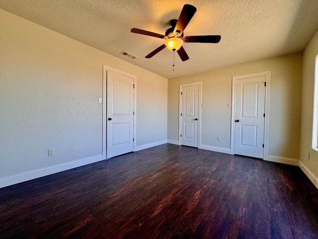 unfurnished bedroom featuring ceiling fan, dark wood-type flooring, and a textured ceiling