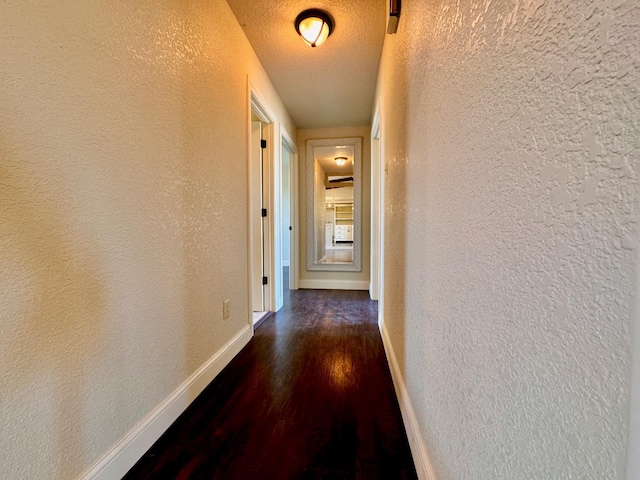 hallway with dark wood-type flooring and a textured ceiling