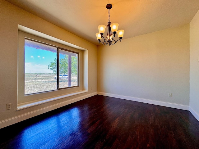 unfurnished room featuring hardwood / wood-style floors and an inviting chandelier