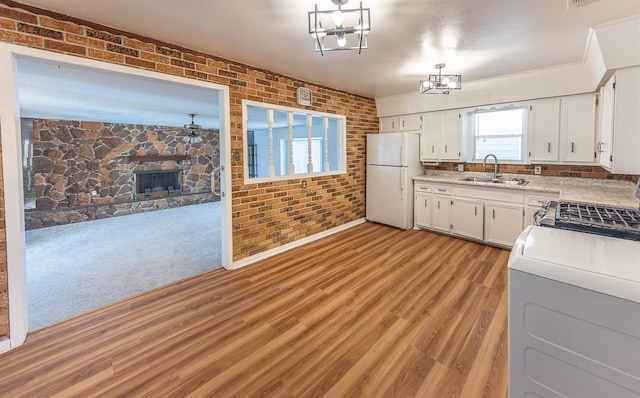 kitchen featuring pendant lighting, sink, white cabinetry, white refrigerator, and a fireplace