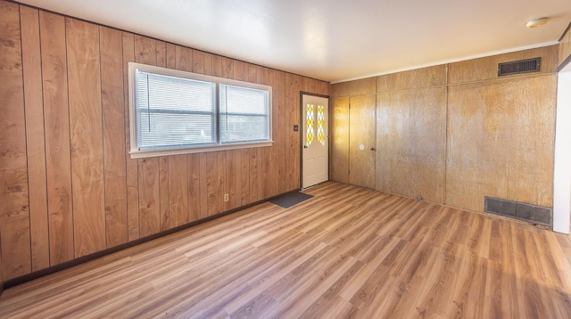 spare room featuring wooden walls and light hardwood / wood-style floors