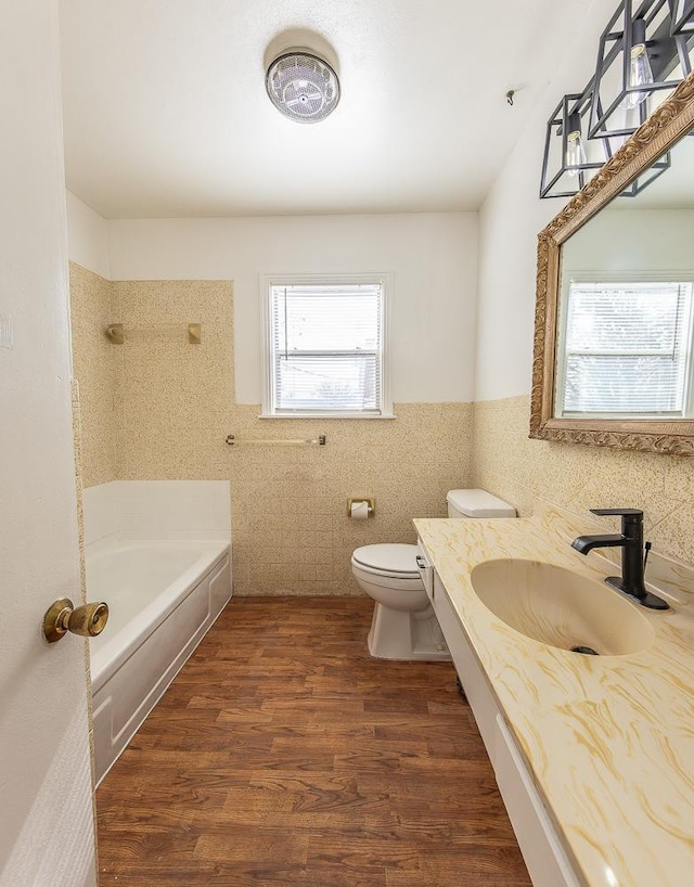 bathroom featuring a washtub, sink, hardwood / wood-style flooring, tile walls, and toilet