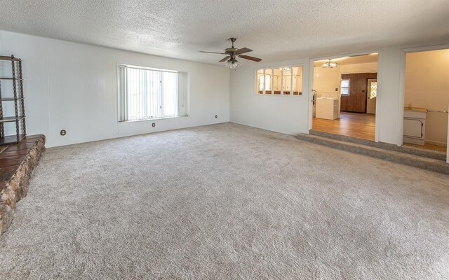 unfurnished living room featuring washer / clothes dryer, ceiling fan, carpet flooring, and a textured ceiling