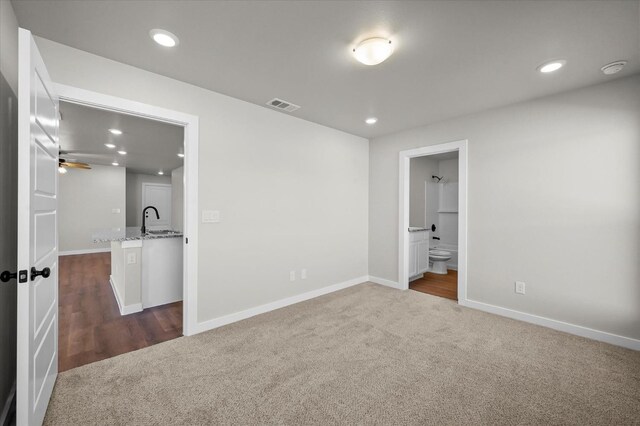 unfurnished bedroom with connected bathroom, sink, and dark colored carpet