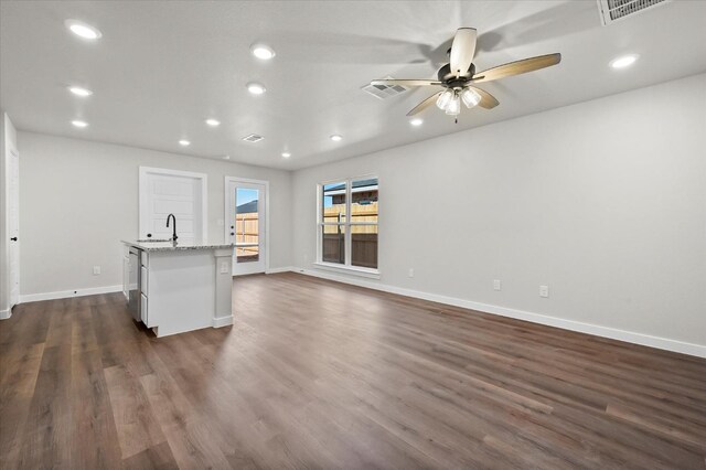 unfurnished living room featuring ceiling fan, sink, and dark hardwood / wood-style flooring