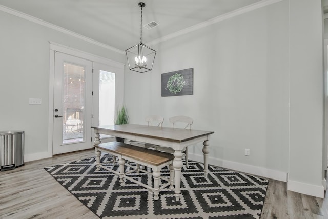 dining area with a notable chandelier, crown molding, and light hardwood / wood-style floors