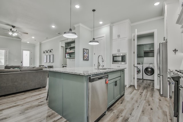 kitchen with pendant lighting, sink, appliances with stainless steel finishes, white cabinetry, and an island with sink