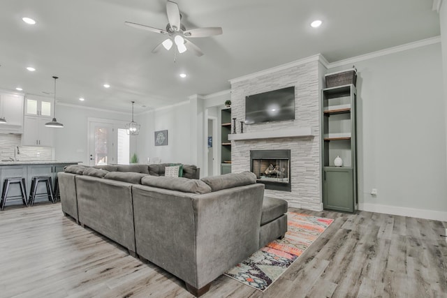 living room featuring ornamental molding, a stone fireplace, and light hardwood / wood-style flooring