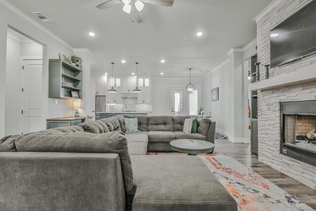 living room with sink, ornamental molding, dark hardwood / wood-style floors, a fireplace, and ceiling fan with notable chandelier