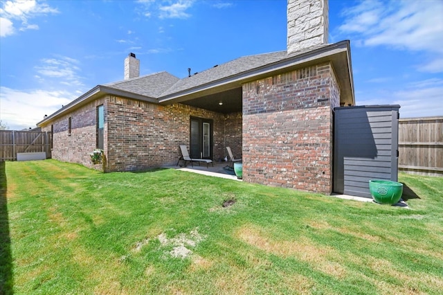 rear view of house with a patio and a lawn