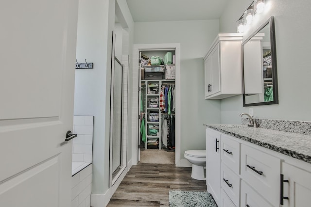 bathroom with vanity, toilet, an enclosed shower, and hardwood / wood-style floors