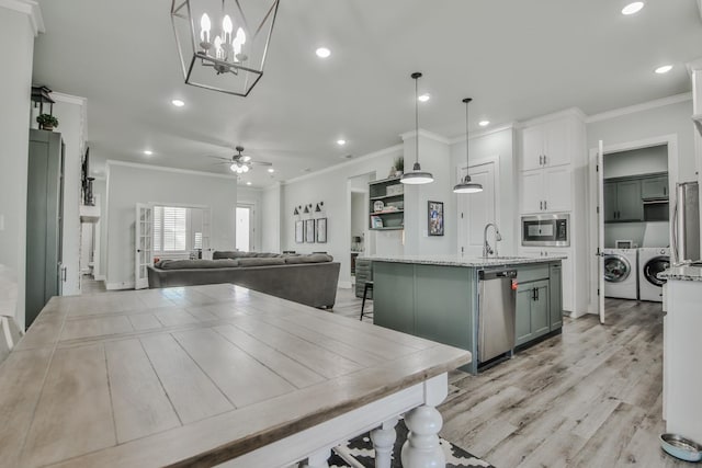 kitchen featuring pendant lighting, washer and clothes dryer, appliances with stainless steel finishes, light stone counters, and white cabinets