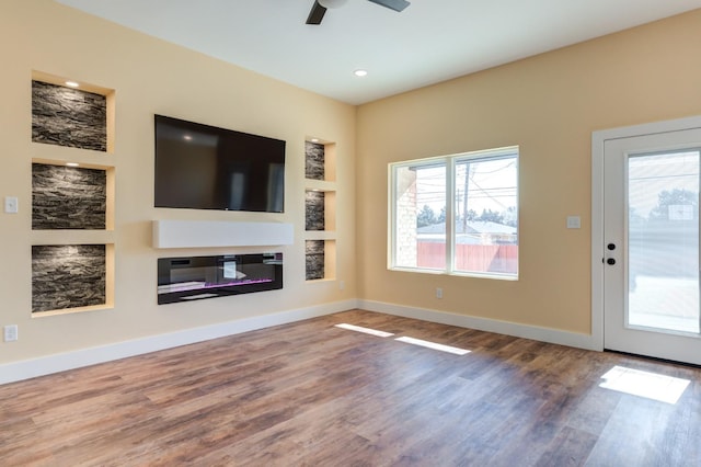 unfurnished living room featuring hardwood / wood-style floors, built in features, and ceiling fan