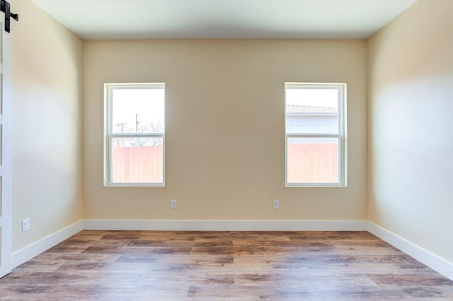 spare room featuring a barn door, plenty of natural light, and light hardwood / wood-style floors