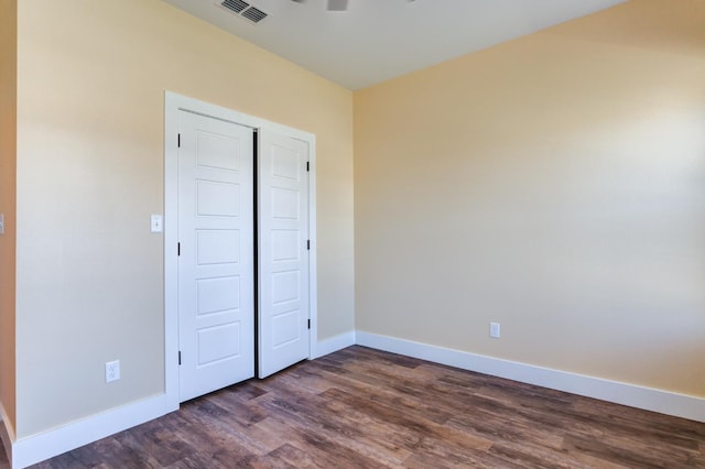 unfurnished bedroom featuring ceiling fan, dark hardwood / wood-style flooring, and a closet