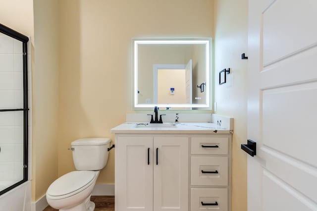 full bathroom featuring vanity, combined bath / shower with glass door, and toilet