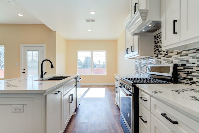 kitchen featuring white cabinetry, appliances with stainless steel finishes, a kitchen island with sink, and sink