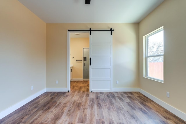 spare room with a barn door and light hardwood / wood-style flooring